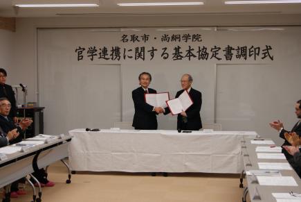 協定書を手に握手を交わす名取市長と理事長